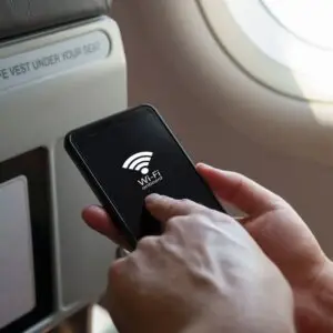 A passenger using a smartphone in an aircraft cabin, connecting to inflight Wi-Fi