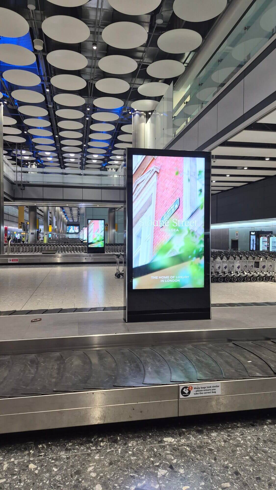 Sloane Street Chelsea street-scene creative, airport OOH advertising on a digital totem unit at London Heathrow baggage reclaim